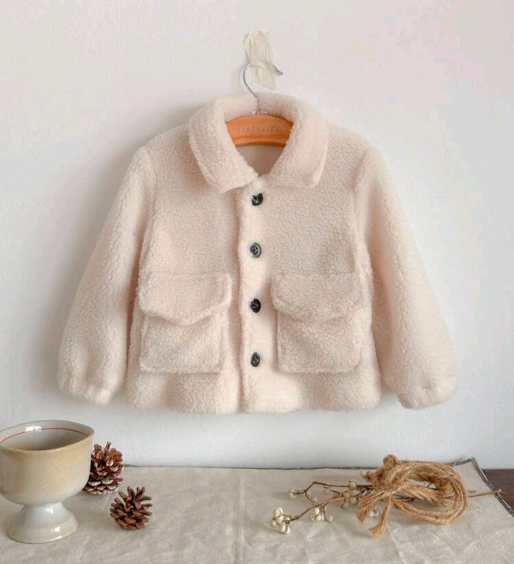 Baby cream teddy faux fur coat with dark button closure and front patch pockets on wooden hanger